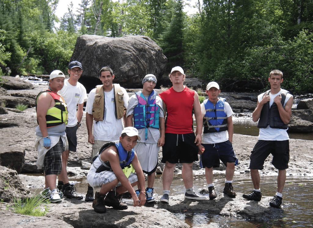Malberg to Koma Lake portage; standing left to right: Soua, Brian, Phil, Joe, Cody, Cham and Cole; Kong is kneeling in front.