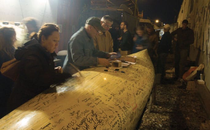 Attendees at a Paddle to D.C. event at the North Brooklyn Boat Club in New York City sign their names on the Freemans’ canoe