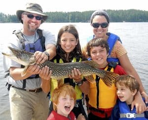 Joseph Goldstein, 13 (center, holding northern pike) is in Washington this week lobbying government officials against copper mining near the BWCAW. He's pictured here in a photo form last summer with Ely guide Jason Zabokrtsky, left, his mother, Kemia Sarraf, right, and his little brothers Jacob, Jonah and Joshua. (Photo by Jeff Goldstein)