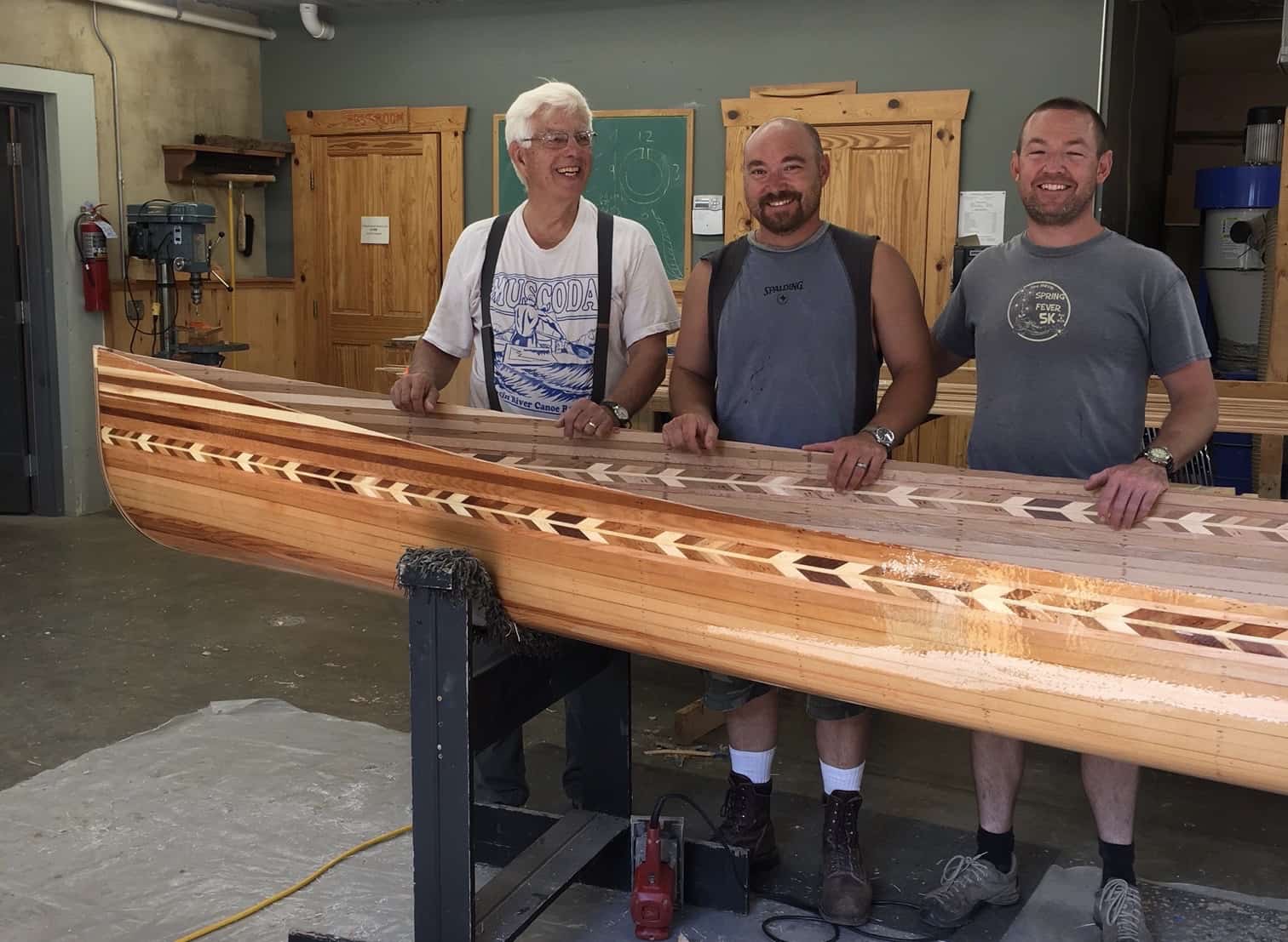 Ken Koscik and two of his students with a wood strip canoe they are building. Photo courtesy Ken Koscik. 
