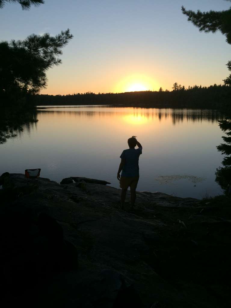Nancy Sorenson looks out over the sunset during her trip to the Boundary Waters with Women's Wilderness Discovery. Photo by Peta Barrett.