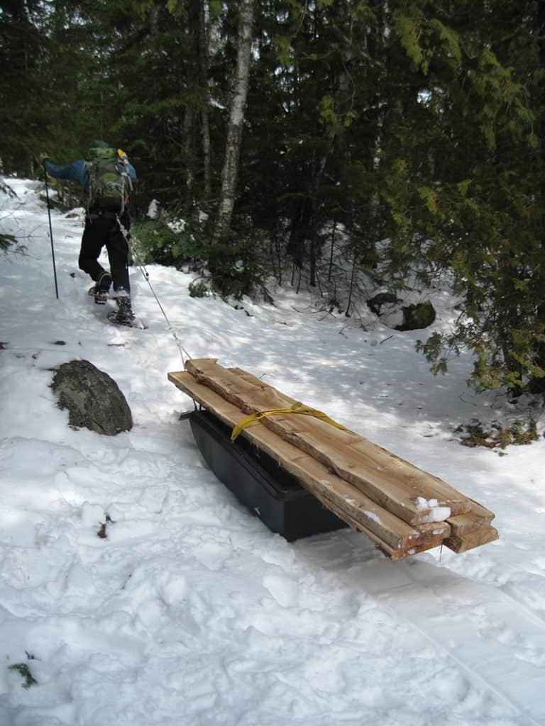 Upon reaching a portage, Blaisdell switches to snowshoes to navigate the difficult terrain with his load of boardwalk materials. Photo courtesy Cathy Quinn. 