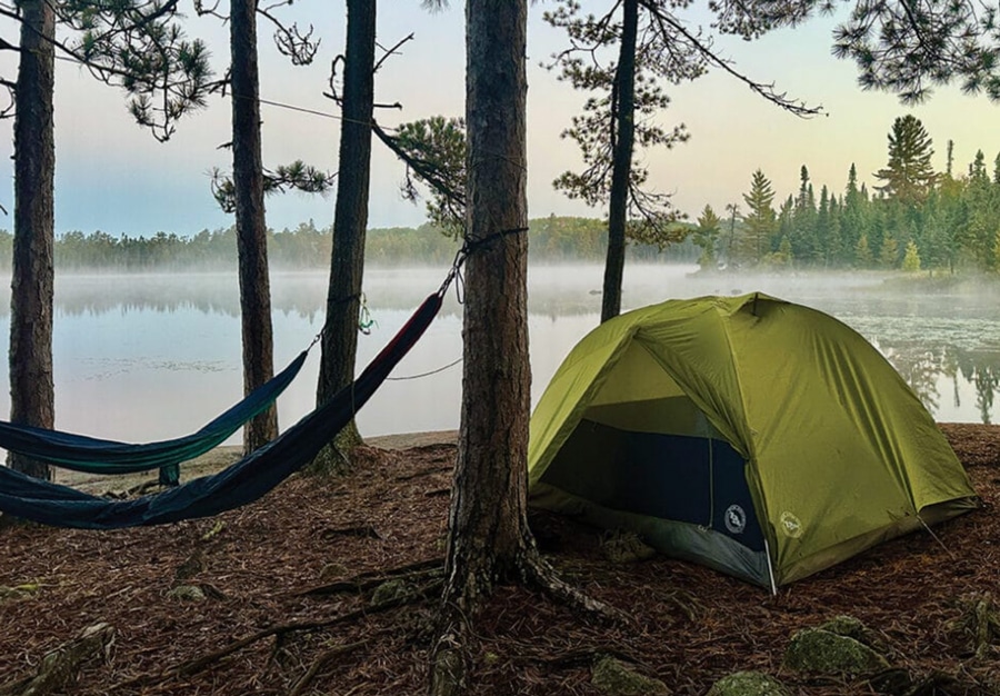 Tent and hammock near shoreline in Boundary Waters foggy morning