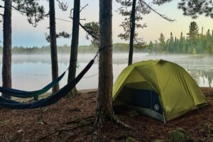Tent and hammock near shoreline in Boundary Waters foggy morning